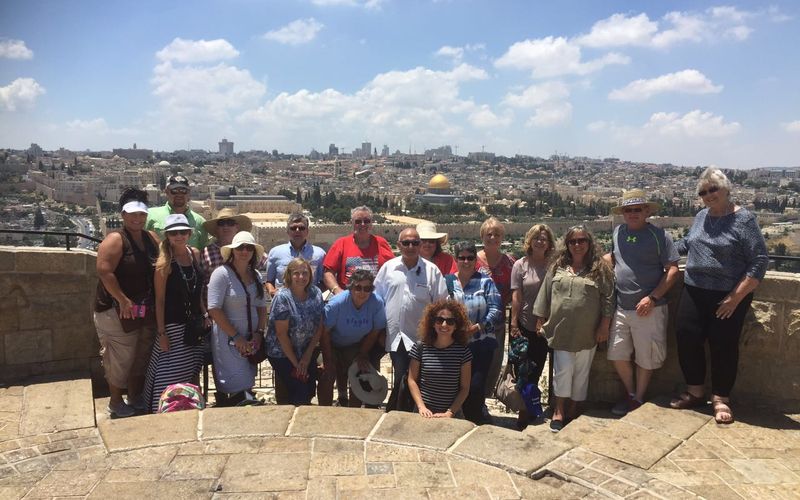A church group tour posing in sunshine at the Mount of Olives overlook above Jerusalem's Old City and the Dome of the Rock